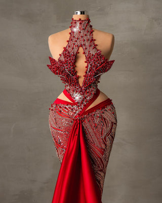 A striking red evening gown adorned with delicate pearls along the neckline and bodice, featuring a sleek silhouette that hugs the body for an elegant and bold look.