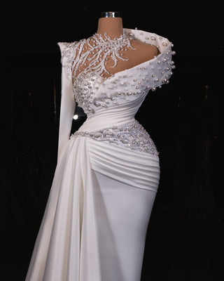 Elegant one-shoulder bridal gown with pearl details and a flowing train.