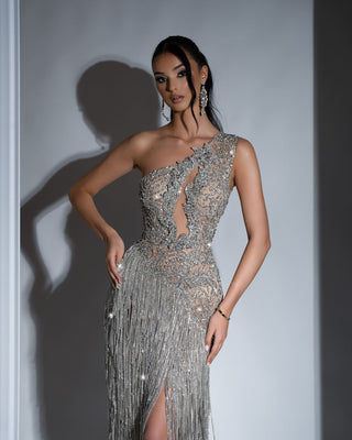 Maxi-length silver dress adorned with tassels and crystals, showcasing a bold one-shoulder design and deep slit