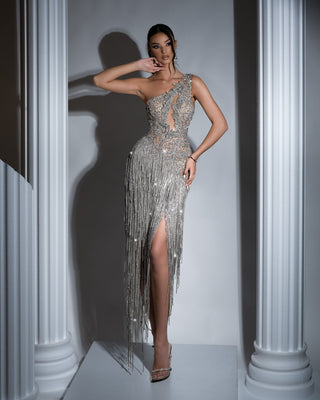Elegant one-shoulder silver dress with tassels and crystals, featuring a deep slit and chest cut-out