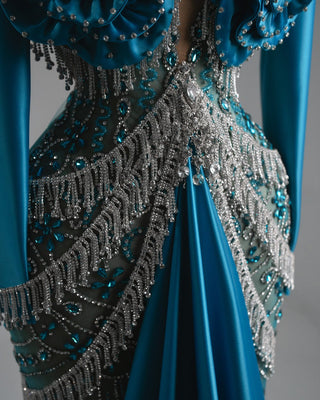 Dramatic teal dress featuring a beaded bodice and train.