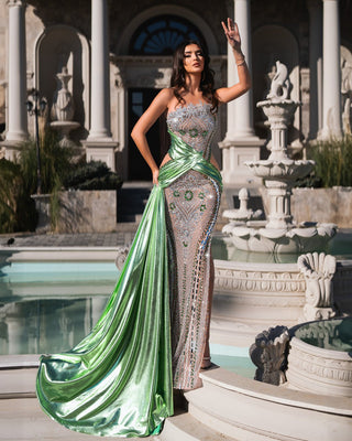 Sparkling emerald dress with a flowing satin train in an outdoor luxury setting.