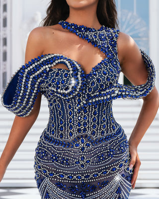 A close-up of a blue dress featuring intricate silver stone embellishments on luxurious fabric.