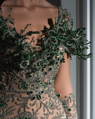 Close-up of intricate green and silver crystal embellishments on a silver dress