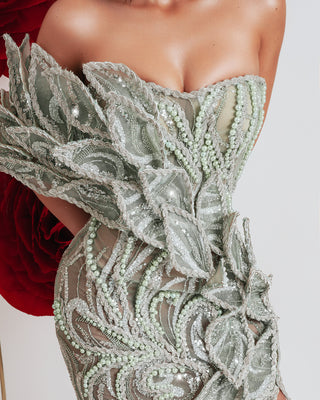 Close-up of sleeveless dress showcasing intricate 3D leaf embellishments and light green beadwork.