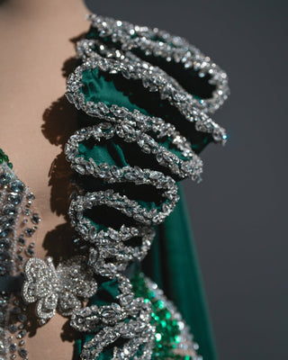 Elegant emerald dress with cascading crystal strands and a regal cape.