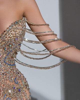 Close-up of intricate crystal embellishments on gold dress with asymmetrical neckline
