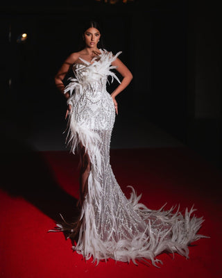 A glamorous white bridal gown with feathers, shimmering sequins, and a dramatic floor-length train.