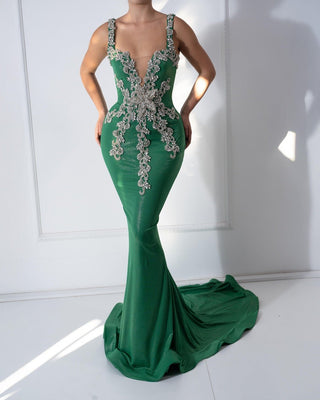 Green dress with crystals, asymmetrical neckline, and flowing skirt.