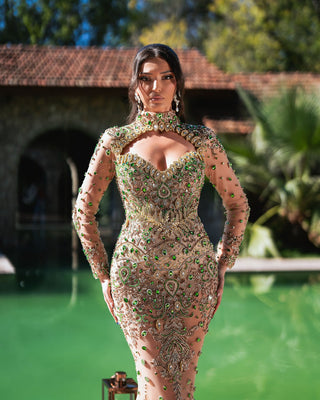 Handmade Makena nude dress with shimmering green crystal embellishments, flowing into a long, elegant silhouette.