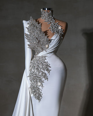 One-shoulder bridal gown in luxurious white with crystal and pearl leaf-like embellishments.