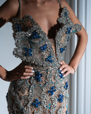 Close-up of chest cut-out and blue crystal embellishments on silver dress
