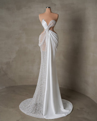 Modern bridal gown with cutouts, crystal details, and flowing satin fabric, blending bold design with timeless grace.