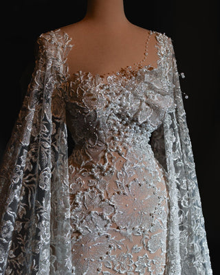 Glamorous wedding dress with delicate lace and dramatic cape sleeves.