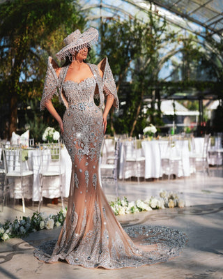  The Vivienne Long Dress, featuring delicate crystal embellishments and a fashionable fedora hat, transforms the greenhouse into a realm of elegance.