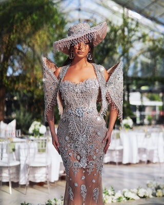 Embracing the allure of the Vivienne Long Dress, this enchanting look showcases intricate crystal details and a stylish fedora hat.