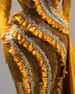 Elegant yellow gown with long sleeves, open chest, and intricate crystal details.