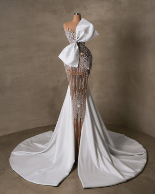 Glamorous wedding dress featuring intricate beadwork, cascading fringe, and a dramatic bow.