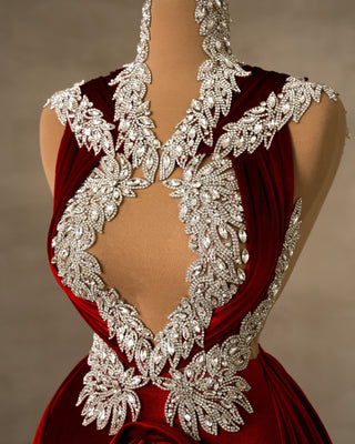 Close-up of the intricate silver embellishments on the bust of a red velvet dress.